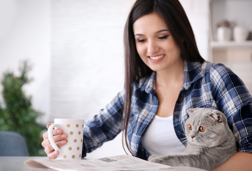 猫を抱きながら新聞を読む女性