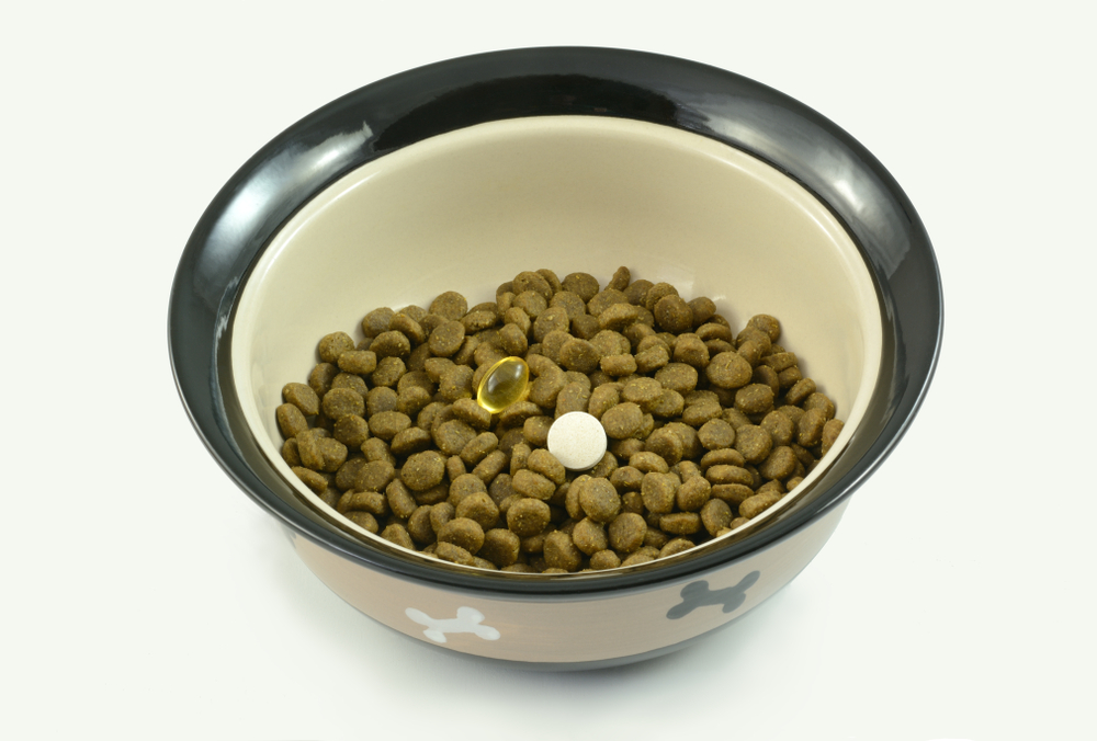 Dog food supplements of fish oil and glucosamine for older dogs with arthritis and dog athletes for joint health placed in bowl of dog food