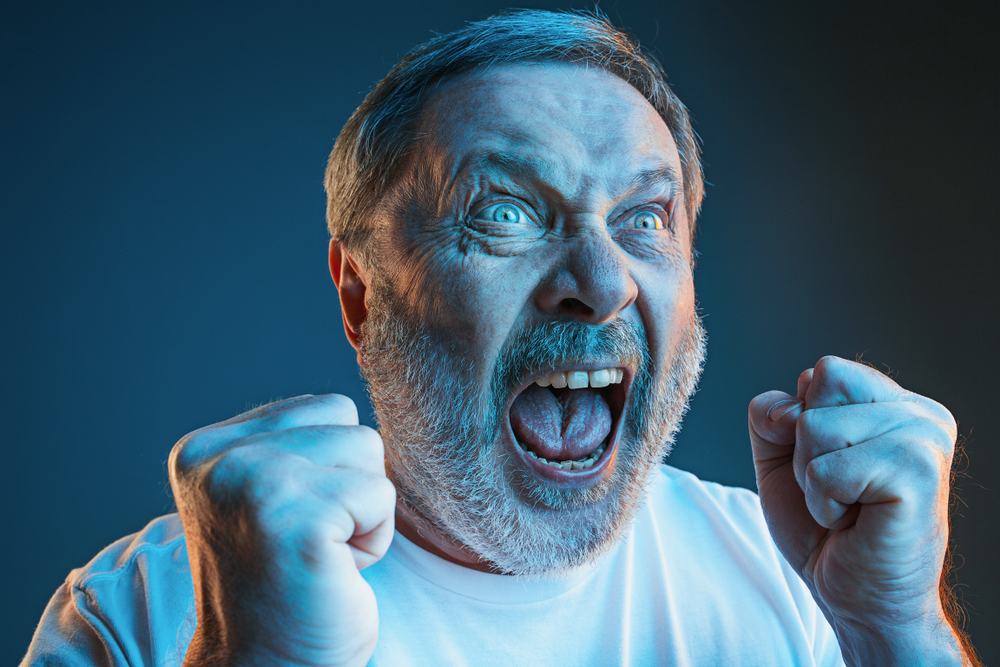Screaming, hate, rage. Crying emotional angry man screaming in colorful bright lights at studio background. Emotional, mature face. male half-length portrait. Human emotions, facial expression concept