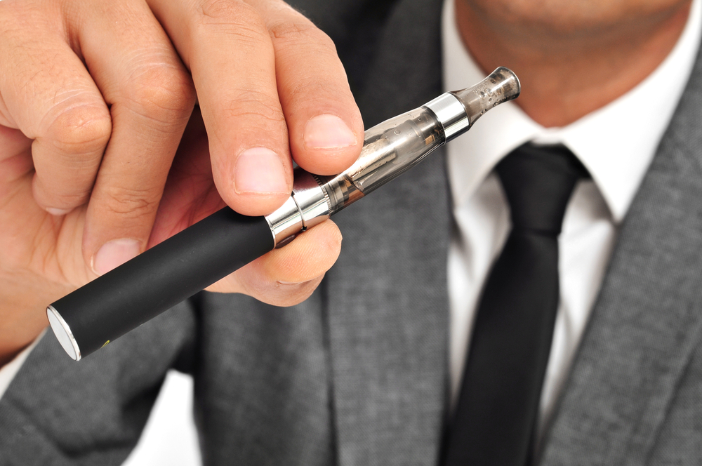 man wearing a suit vaping with an electronic cigarette