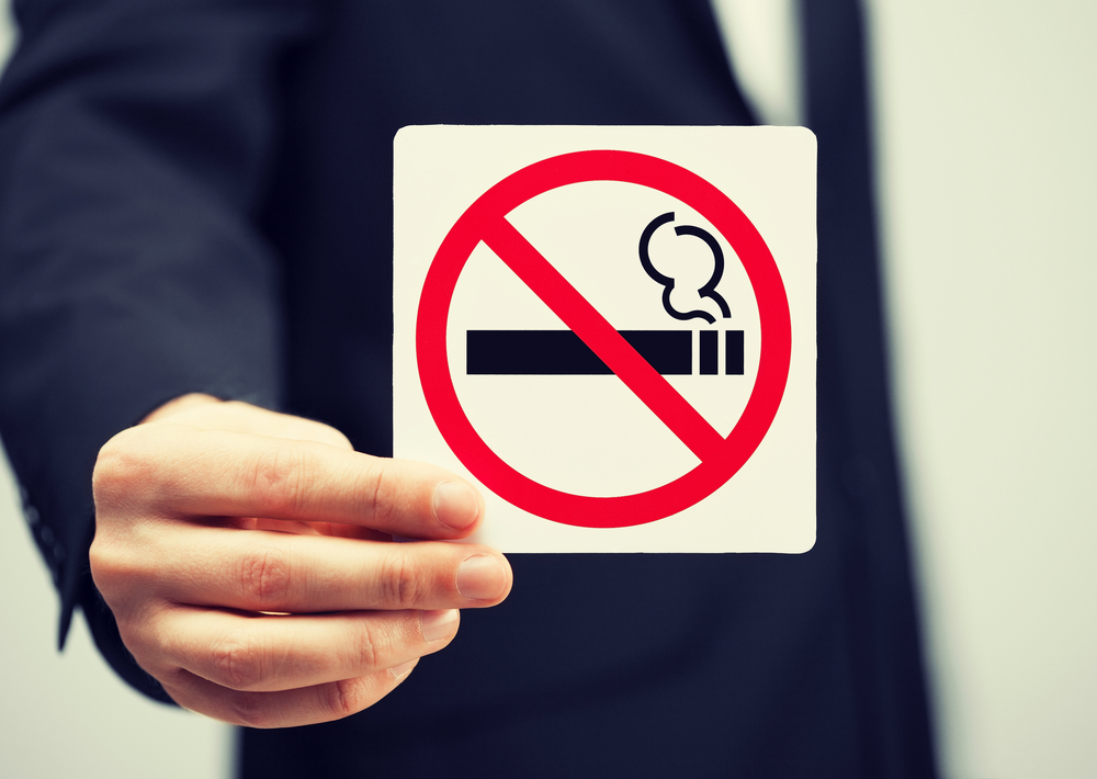 picture of man in suit holding no smoking sign
