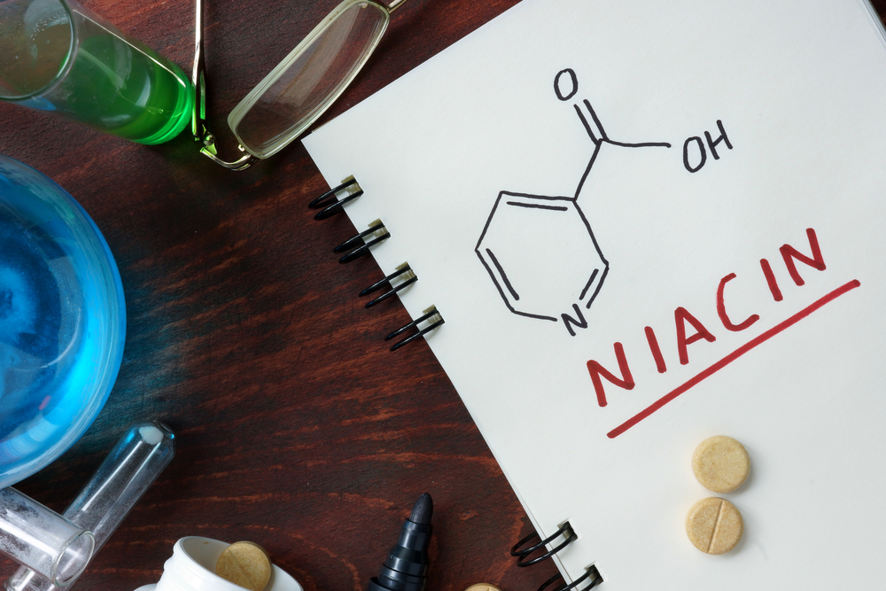 Notepad with chemical formula of  Niacin (vitamin b3) on the wooden table.