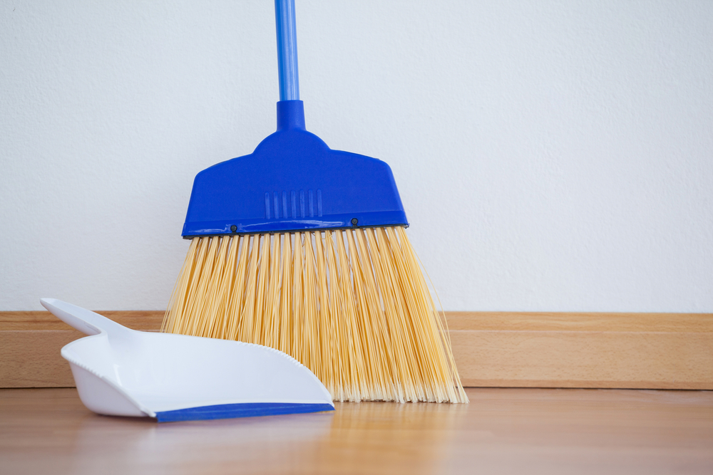 Close-up of dustpan and sweeping broom on wooden floor